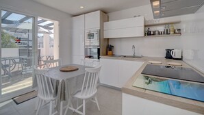 A modern kitchen with white cabinetry, a dining area with a glass table, and a view of the outside. - Exclusive Duplex Penthouse with panoramic views  (Marbella)