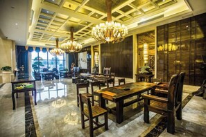 A spacious dining area with a high ceiling and chandeliers, featuring a polished marble floor and wooden furniture. - Binhu Hotel (Hanchuan)