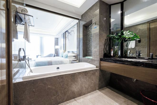 A modern bathroom with a large bathtub, a mirror, and a plant on the counter.