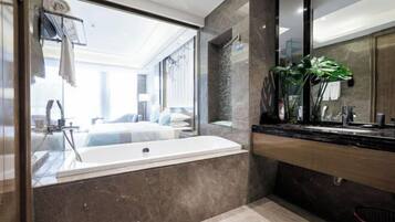 A modern bathroom with a large bathtub, a mirror, and a plant on the counter.