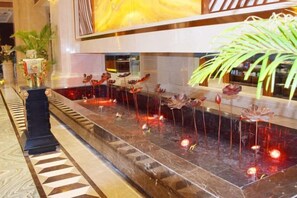 A lobby with a long, narrow water feature with flower-shaped decorations and a reflective surface. - Binhu Hotel (Hanchuan)