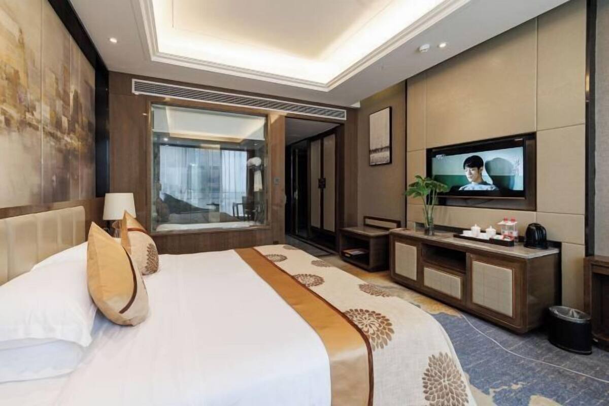 Een hotelkamer met een groot bed, een televisie, een bureau en een raam.