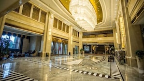 A spacious lobby with a large chandelier, a central fountain, and a seating area with a checkered floor pattern. - Binhu Hotel (Hanchuan)