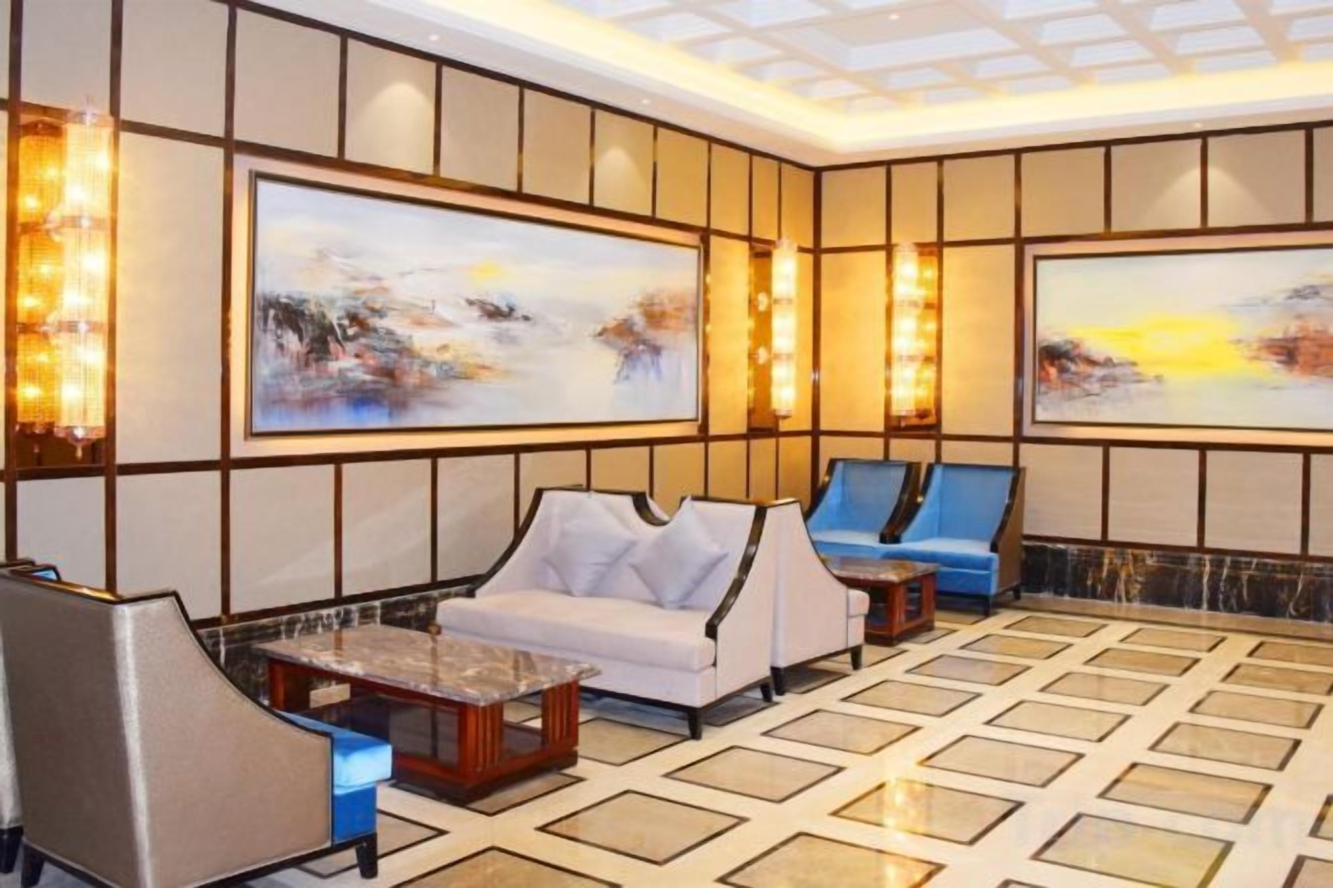 A lobby with a seating area, large paintings, and a patterned floor.