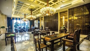 A spacious lobby with a large wooden reception desk, multiple seating areas, and a chandelier. - Binhu Hotel (Hanchuan)