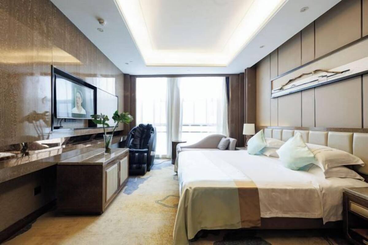 Een hotelkamer met een bed, nachtkastje, televisie en een bureau met een stoel.