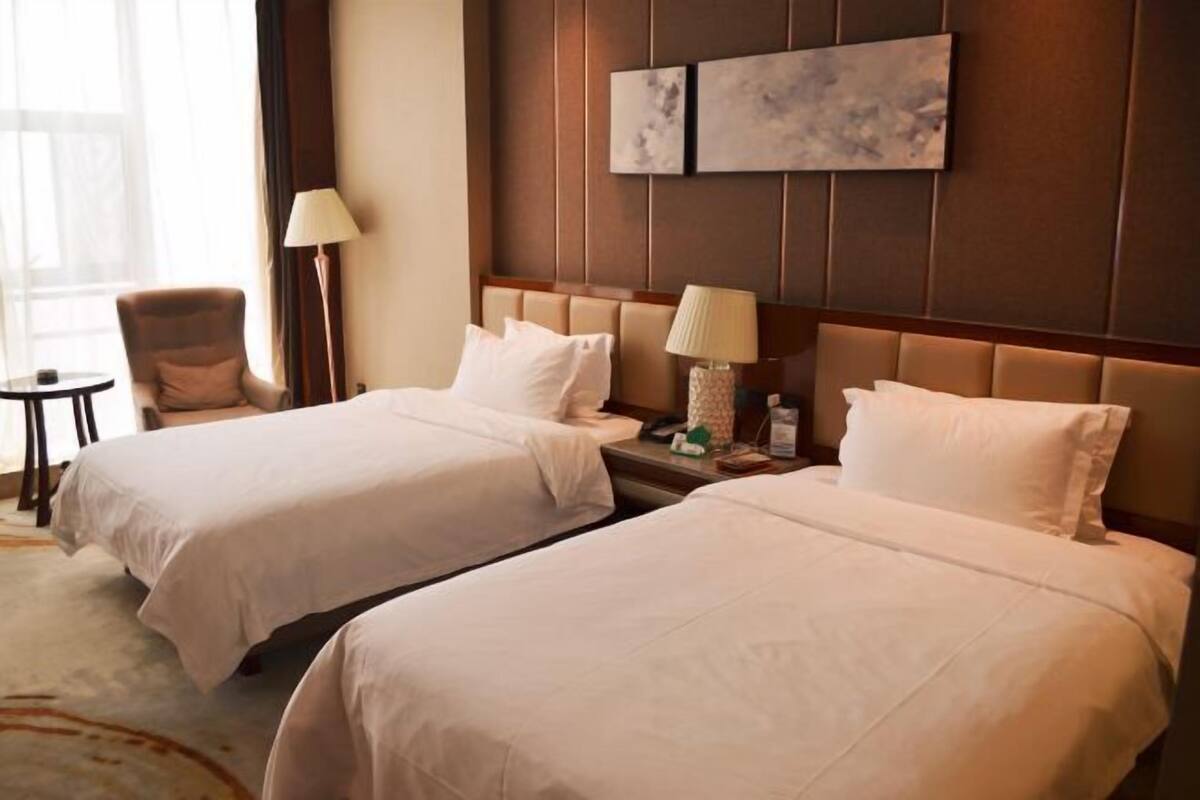 Een hotelkamer met twee bedden, een nachtkastje, een lamp en een stoel.