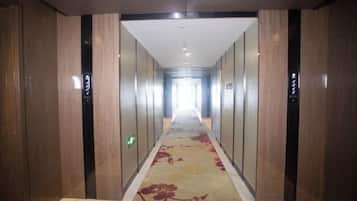 A long, narrow hallway with a carpeted floor and wooden paneling on the walls.
