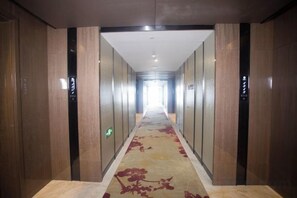 A long, narrow hallway with a carpeted floor and wooden paneling on the walls. - Binhu Hotel (Hanchuan)