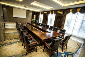 A conference room with a long table, multiple chairs, and a projector screen. - Binhu Hotel (Hanchuan)