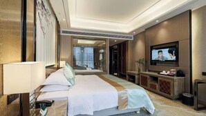 A hotel room with a bed, a television, a desk, and a mirror. - Binhu Hotel (Hanchuan)