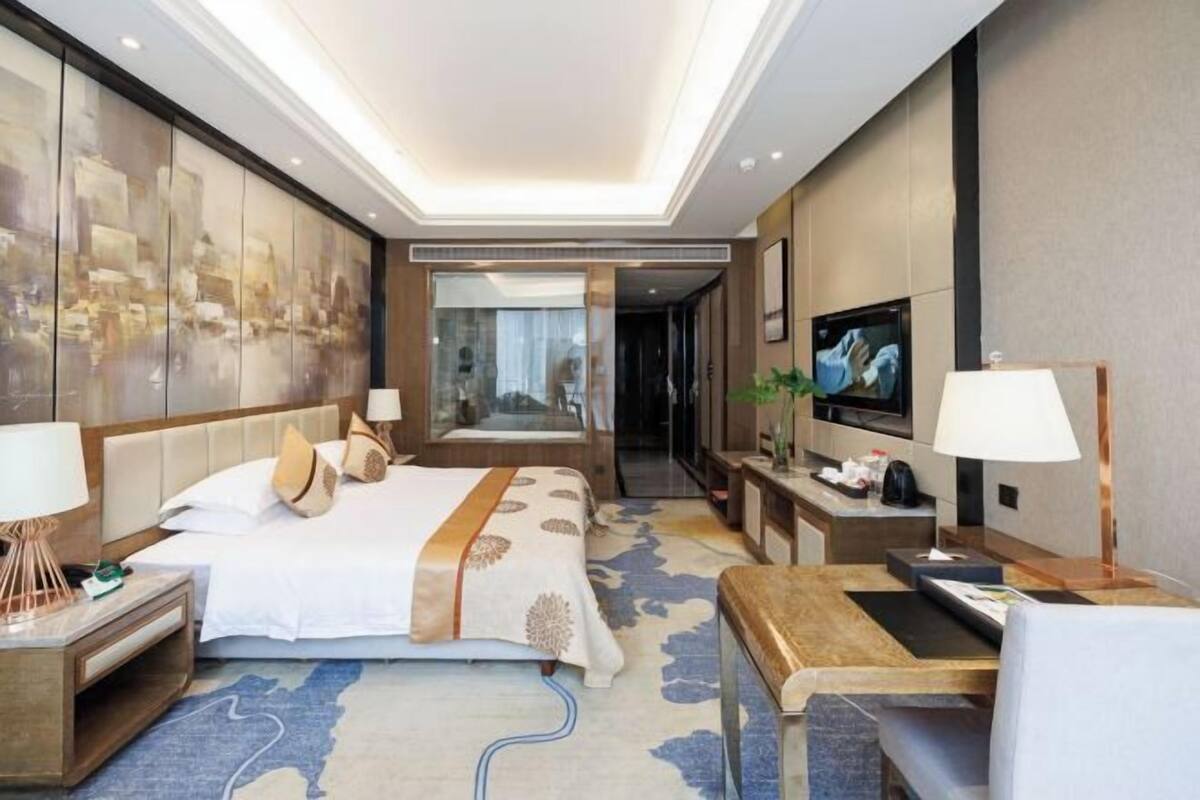 Een moderne hotelkamer met een groot bed, nachtkastjes, een televisie en een spiegel.