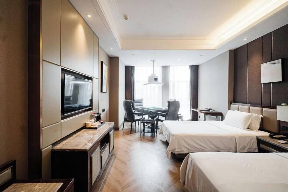 Een hotelkamer met twee bedden, een bureau, een televisie en een eethoek.