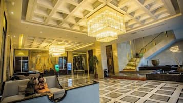 A hotel lobby with a chandelier, seating area, and a staircase.