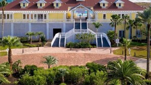 A hotel with a central staircase, palm trees, and a view of the ocean. - Beautiful Pointe West Beach House w/Great Sunsets, Beach, Bay Views & Pet Ok (Galveston)