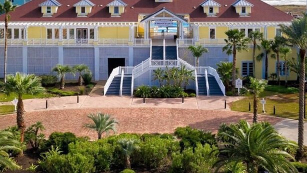 A hotel with a central staircase, palm trees, and a view of the ocean. - Beautiful Pointe West Beach House w/Great Sunsets, Beach, Bay Views & Pet Ok (Galveston)