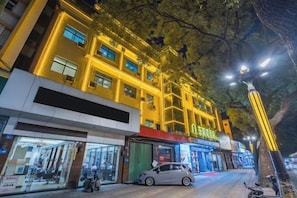 A multi-story building with illuminated windows and a tree in front. - South East Bay Hotel (Huizhou West Lake Pedestrian Street) (Huizhou)