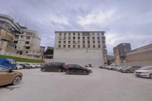 A parking lot with several cars, a large building with multiple floors, and a clear sky. - South East Bay Hotel (Huizhou West Lake Pedestrian Street) (Huizhou)