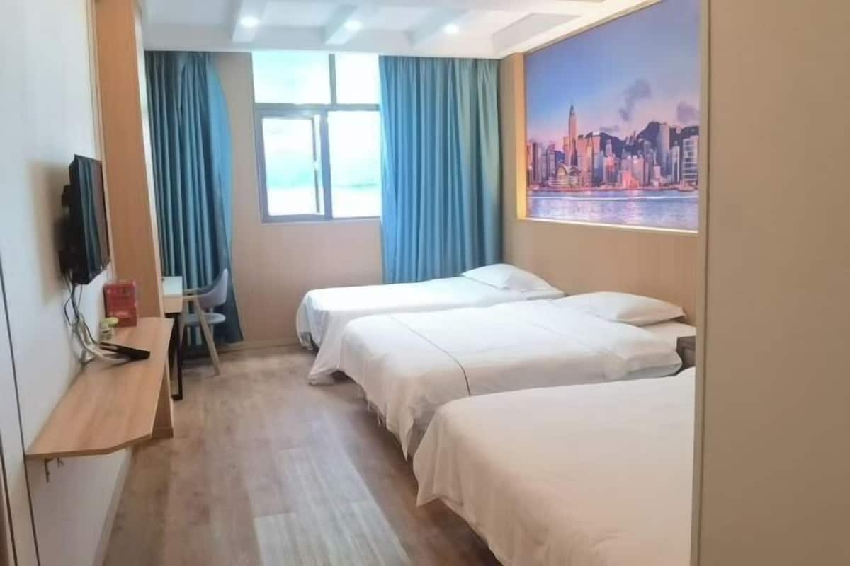 A hotel room with two beds, a desk with a chair, a TV, and a window with curtains.