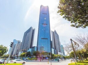 A high-rise building with a modern glass facade, surrounded by trees and other buildings. - South East Bay Hotel (Huizhou West Lake Pedestrian Street) (Huizhou)