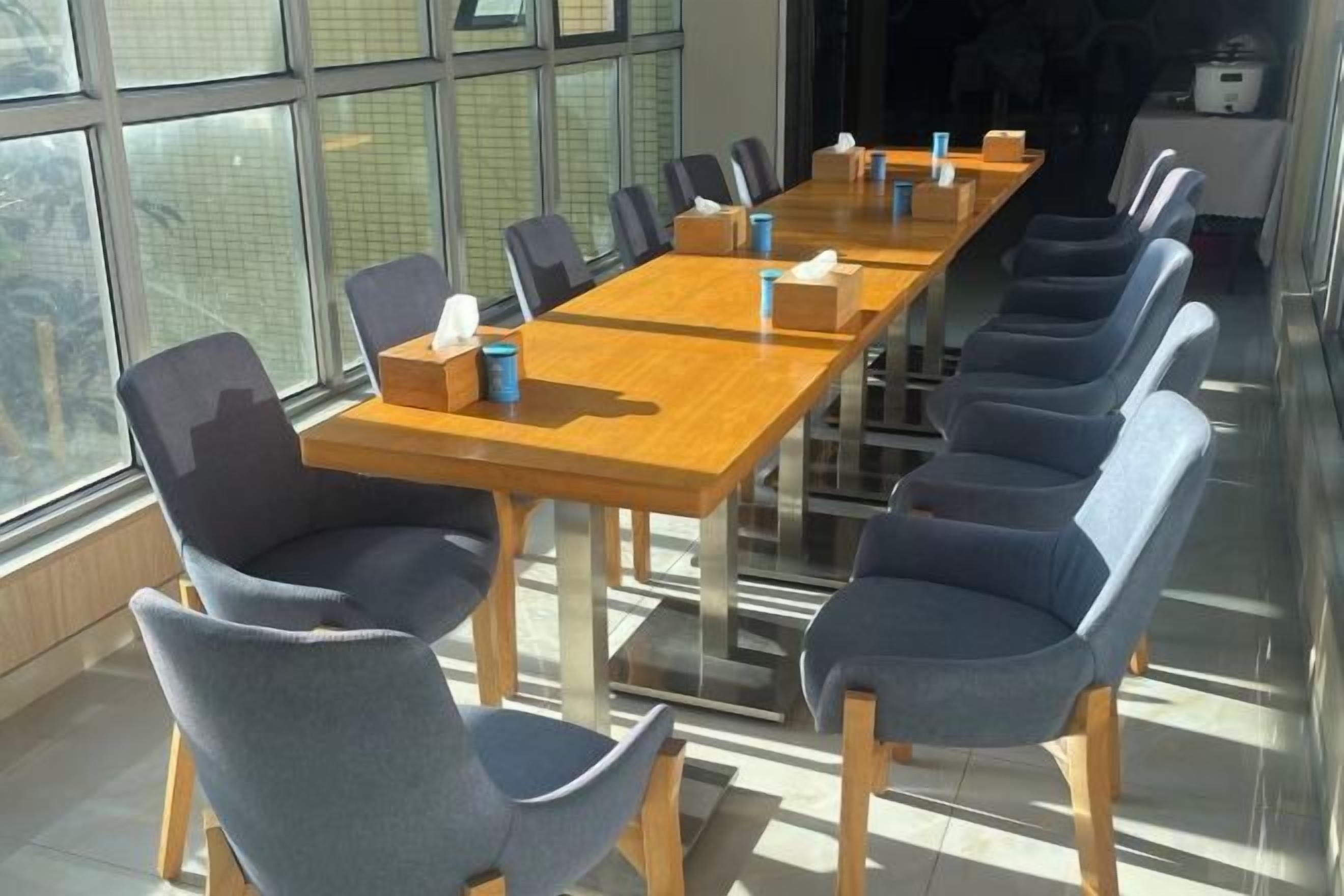 A conference room with a long table and chairs, equipped with tissues and cups.
