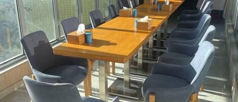 A conference room with a long table and chairs, equipped with tissues and cups.