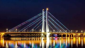 A nighttime view of a cable-stayed bridge with its lights reflecting on the water.