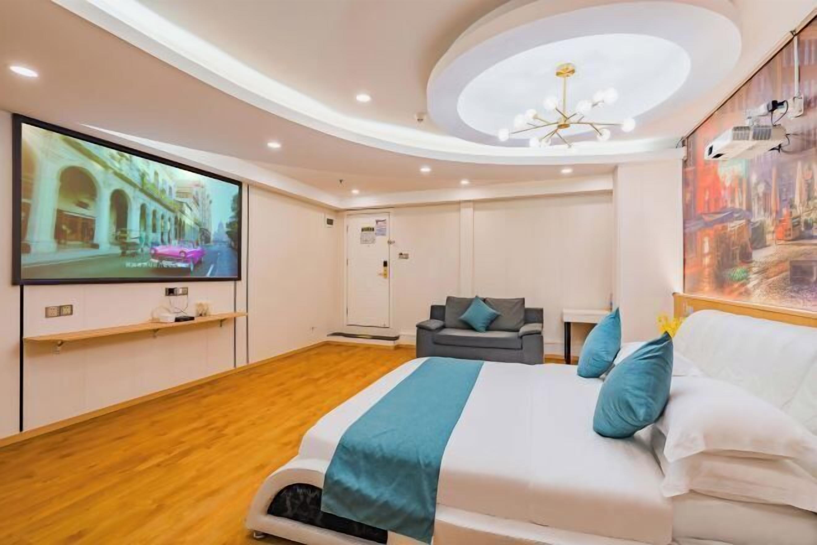A hotel room with a large bed, a TV mounted on the wall, a desk, and a chair.