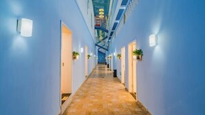 Ein Hotelgang mit blauen Wänden, einem gefliesten Boden und einer zentralen Treppe.