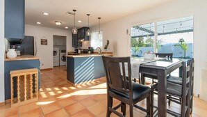 Une cuisine moderne dotée d’un îlot central, d’appareils électroménagers intégrés et de luminaires suspendus.