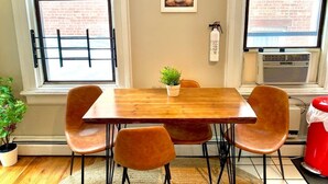 Un coin repas avec une table en bois et quatre chaises, une plante en pot et un extincteur fixé au mur.