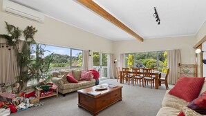 A spacious living room with a large window, a wooden dining table, and a cozy seating area.