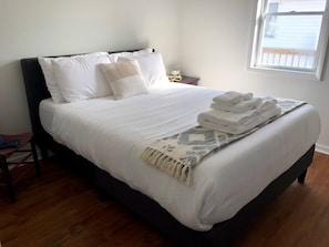 A neatly made bed with white linens and a folded towel on the side. - Waterfront Retreat with Private Dock on the Sound (Kill Devil Hills)