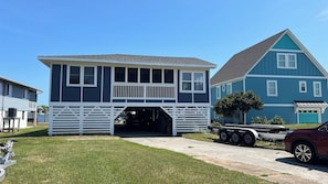 A two-story house with a garage entrance, a flat roof, and a visible truck parked outside. - Waterfront Retreat with Private Dock on the Sound (Kill Devil Hills)