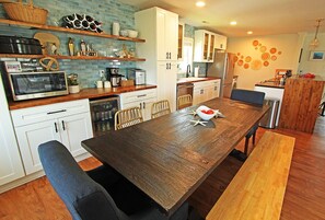 A modern kitchen with white cabinets, a wooden dining table, and a built-in microwave. - Clean and inviting Canal Front Cottage (Kill Devil Hills)