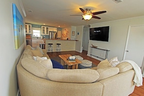 A living room with a sofa, a coffee table, and a TV mounted on the wall. - Waterfront Retreat with Private Dock on the Sound (Kill Devil Hills)