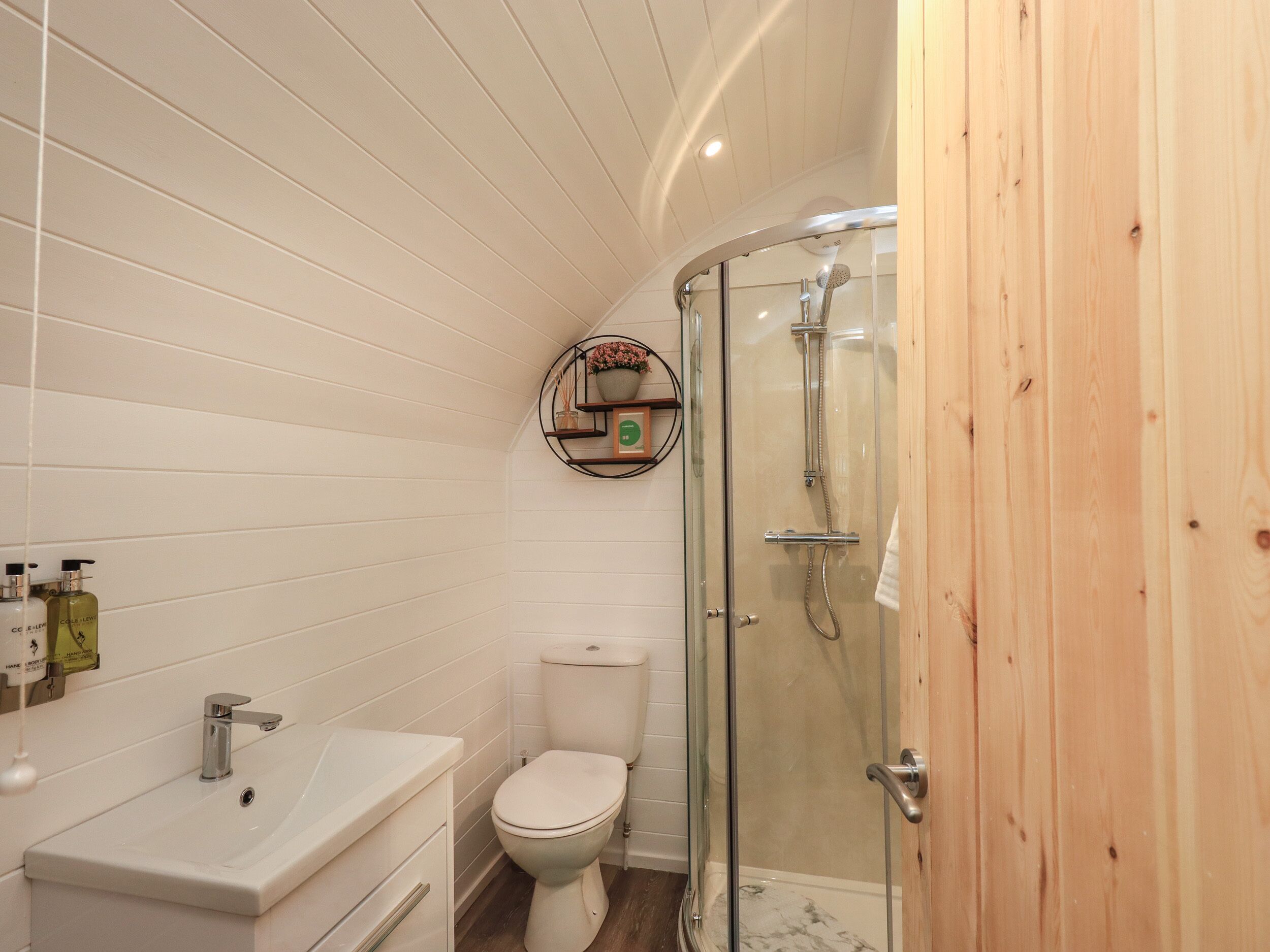 Een badkamer met een wit wastafel, toilet en douche met glazen wanden.