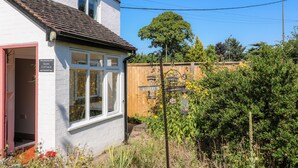A white cottage with a red door, a window with white frames, and a sign reading "HOPS COTTAGE." - Hops Cottage (Ashbourne)