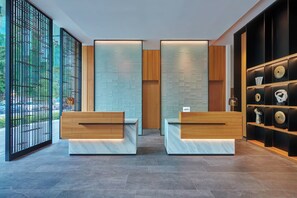 A reception area with two marble reception desks, a wooden panel wall, and a black shelving unit with decorative items.