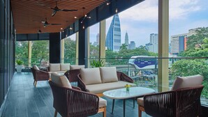 A modern outdoor lounge area with wicker furniture, a round table, and a view of the city skyline. - Fairfield by Marriott Chow Kit Kuala Lumpur (Kuala Lumpur)