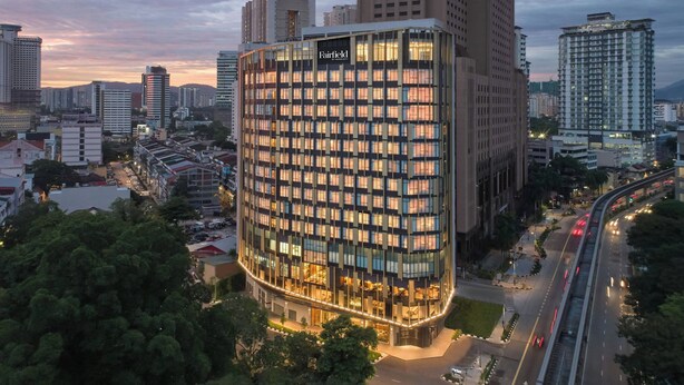 A modern hotel with a distinctive curved facade, surrounded by high-rise buildings and a busy road. - Fairfield by Marriott Chow Kit Kuala Lumpur (Kuala Lumpur)