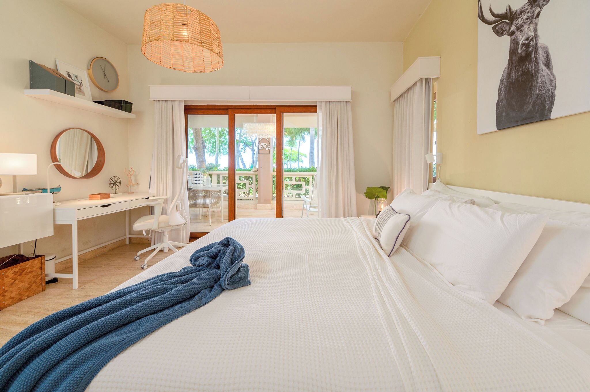 Une chambre d’hôtel avec un lit, un bureau, une chaise, une lampe, une horloge et une fenêtre avec des rideaux.