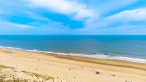 Una spiaggia con cielo sereno, litorale sabbioso e alcune persone.