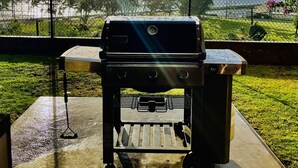 A portable Genesis II grill with a digital display, positioned on a concrete surface outdoors. - Banyan Harbor - Your home away from home! (Lihue)