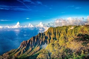 A mountainous landscape with a view of the ocean and clouds.