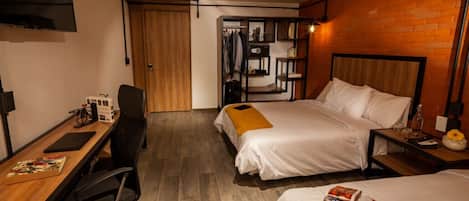 Habitación de hotel con dos camas, un escritorio, una silla, un armario y un televisor.
