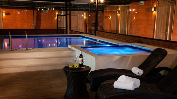 Ein Wellnessbereich mit Whirlpool, Liegestühlen und einem Tisch mit Flasche und Gläsern.