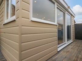 A beige wooden house with a sliding glass door and a window.