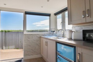 A modern kitchen with a view of the countryside, a built-in microwave, and a large window.