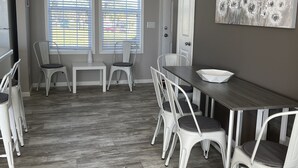 Un coin repas avec une table en bois foncé, des chaises blanches et une porte blanche.